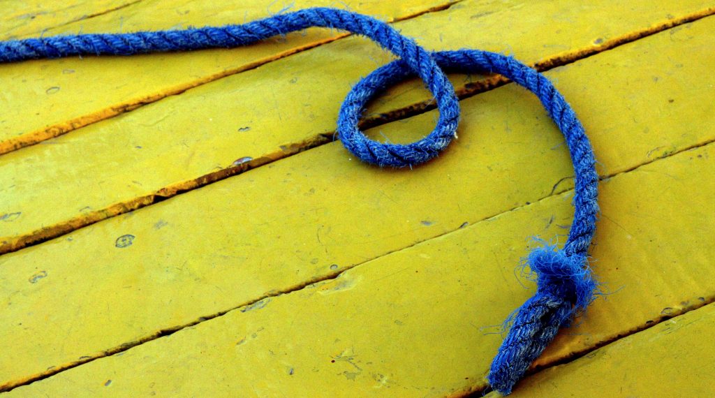 Bewegungsspiel mit Seilen. Blaues Seil auf gelbem Holzboden.